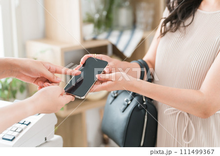 スマホ・スマホ決済・オンライン決済で買い物をする女性とショップ店員 111499367