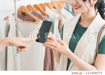 スマホ・スマホ決済・オンライン決済で買い物をする女性とショップ店員 111499373