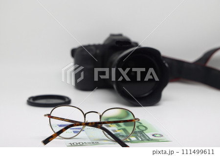 Office desk workplace with camera, glasses and banknotes. Earnings on photo stocks. 111499611