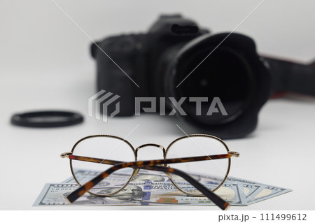 Office desk workplace with camera, glasses and banknotes. Earnings on photo stocks. 111499612