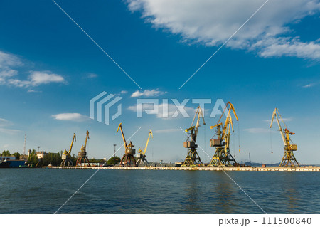 Industrial port with cranes loading cargo on ships, trade hub for freight transport, logistics. Maritime skyline, dockside machinery, export-import operations, container terminal, seaport economy. Industrial port with cranes loading cargo on ships, trade hub for freight transport, logistics. Maritime skyline, dockside machinery, export-import operations, container terminal, seaport economy. 111500840
