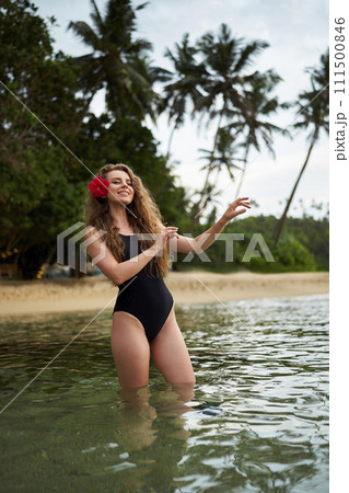Woman performs hula dance in sea, tropical backdrop, flower in hair, travel, Hawaiian culture, serene beach holiday, relax. Cultural dance expression, ocean waves, tourism attraction, summer getaway. 111500846