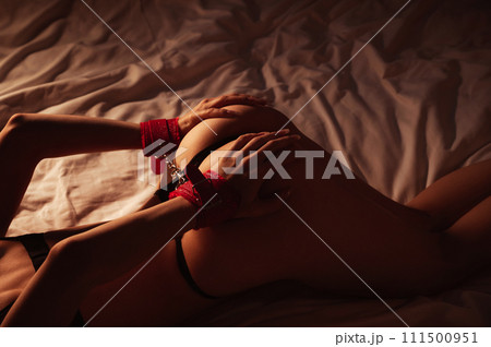 submissive woman girl with a sexy body and a big ass with handcuffed hands lying on bed in bedroom. BDSM sex with submission and domination submissive woman girl with a sexy body and a big ass with handcuffed hands lying on bed in bedroom. BDSM sex with submission and domination 111500951