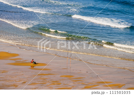 Angler with fishing rod on sea shore 111501035