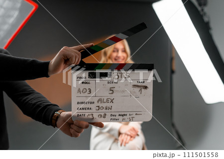 Woman gestures with clapper board in front of man, creating fun event display 111501558
