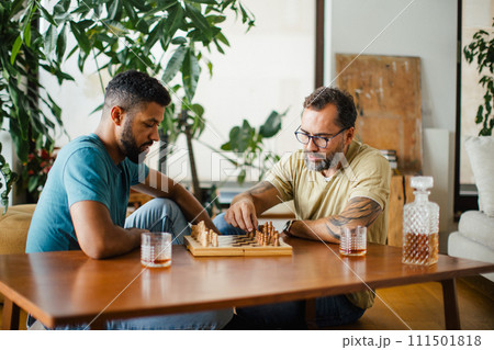 Best friends playing chess together, drinking whiskey and talking. Concept of male friendship, bromance. 111501818