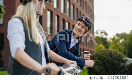 Spouses commuting through the city, talking and walking by bike on street. Middle-aged city commuters traveling from work by bike after a long workday. 111501824