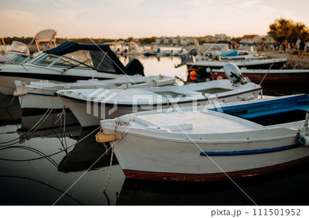 Small boats on calm water, moored in the harbor during sunset. 111501952