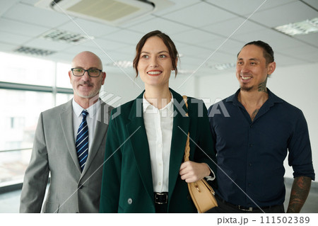 Happy young female business leader in formalwear moving forwards with two intercultural male colleagues or subordinates Happy young female business leader in formalwear moving forwards with two intercultural male colleagues or subordinates 111502389