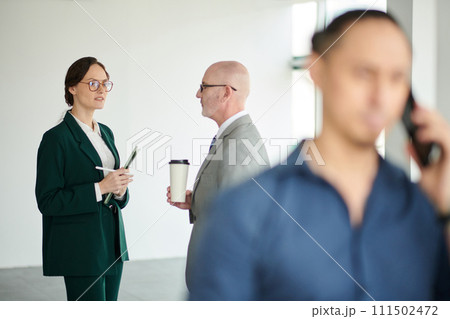 Focus on young female manager with documents standing in front of mature male boss with cup of coffee during conversation at meeting 111502472
