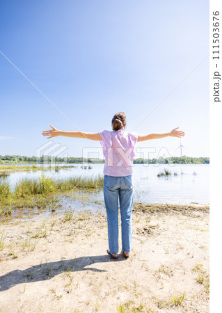 Woman with Outstretched Arms Embracing Nature 111503676