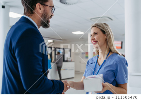 Pharmaceutical sales representative talking with doctor in medical building. Ambitious male sales representative presenting new medication on tablet. 111505470