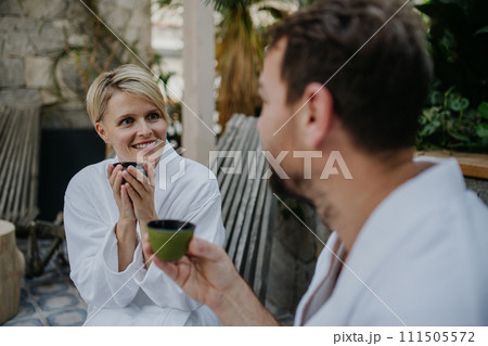 Couple in bathrobes drinking green tea, enjoying romantic wellness weekend in spa. Concept of Valentine's Day. 111505572