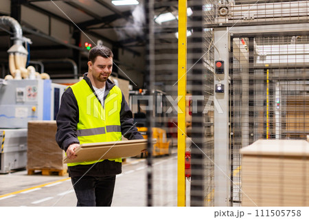 Portrait of young man with Down syndrome working in warehouse. Concept of workers with disabilities, support in workplace. 111505758