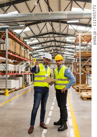 Engineer consulting with foreman in modern industrial factory, talking about new production project or investment. Team management in manufacturing facility. 111505772