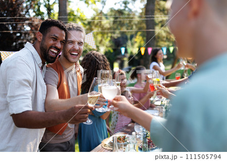 Friends clinking glasses at summer garden party. Celebratory toast at the table. 111505794