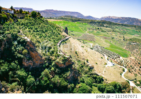 Ronda town and valley, Andalusia, Spain. Popular landmark. Tourist attraction at sunset light, place to visit. View from the city on valley 111507071
