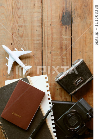 Travel concept with passport, camera, notebook and airplane on wooden background 111508388