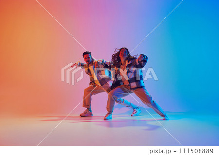 Man and woman, dancing synchronously in motion against gradient studio background. Harmony moves. 111508889