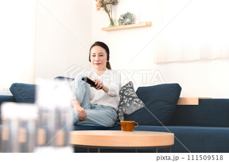 部屋のソファーでテレビを見ながらくつろぐ女性 111509518