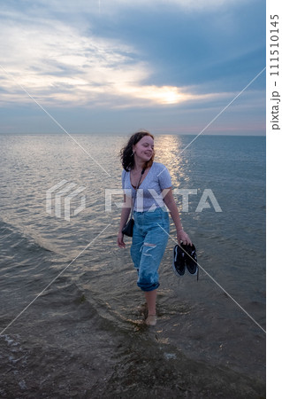 Young Woman Wading in Water at Sunset 111510145