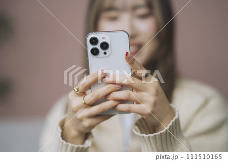 スマートフォンを操作する若い女性の手元 111510165