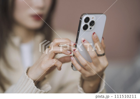スマートフォンを操作する若い女性の手元 111510211