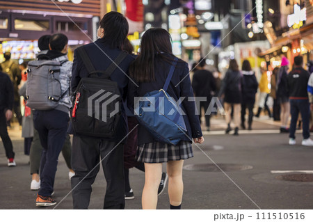 夜の渋谷センター街を歩く制服の女子高生の後ろ姿 111510516