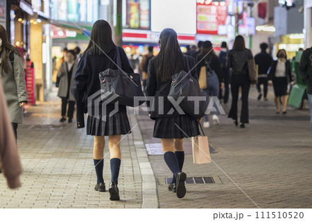 夜の渋谷センター街を歩く制服の女子高生の後ろ姿 111510520