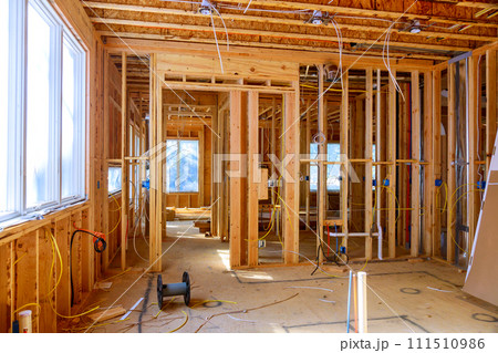 Worker installs electrical wires, insulation, and ceiling light before plasterboard in new house Worker installs electrical wires, insulation, and ceiling light before plasterboard in new house 111510986