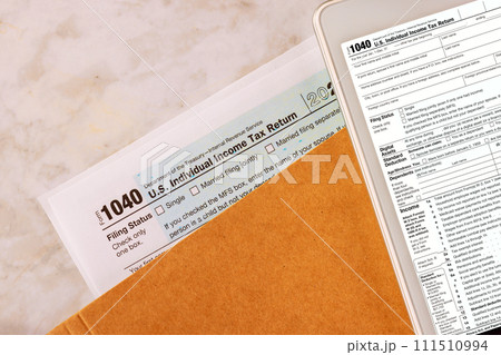 Filing online on digital tablet with individual income tax form 1040 is prepared by accounting office during tax season 111510994