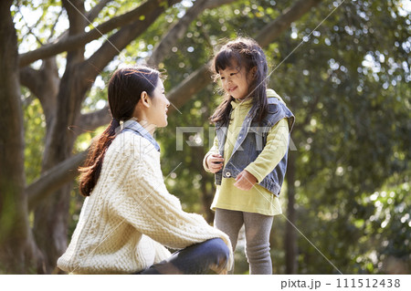 young asian mother talking to daughter outdoors in park young asian mother talking to daughter outdoors in park 111512438