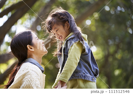 young asian mother talking to daughter outdoors in park 111512546