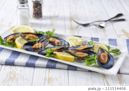 Cooked mussels with lemon and parsley on wooden table, selective focus. Cooked mussels with lemon and parsley on wooden table, selective focus. 111514408