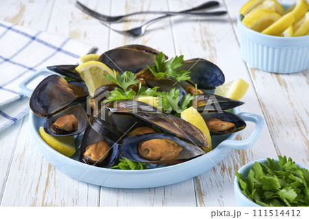 Close up of a plate with  cooked mussels on white table, selective focus. 111514412