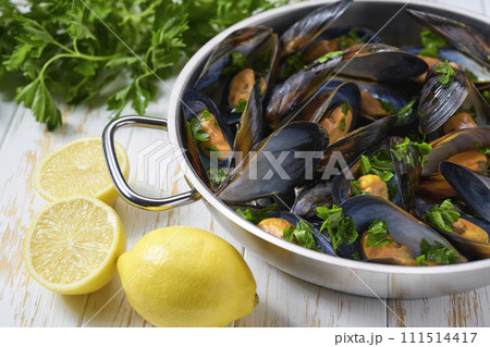 Mussels with french fries and herbs in cooking pan. White background. Close up. Mussels with french fries and herbs in cooking pan. White background. Close up. 111514417