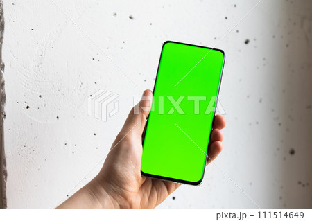 Mockup image of a person holding smart mobile phone with blank green screen. 111514649