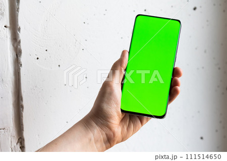 Mockup image of a person holding smart mobile phone with blank green screen. 111514650