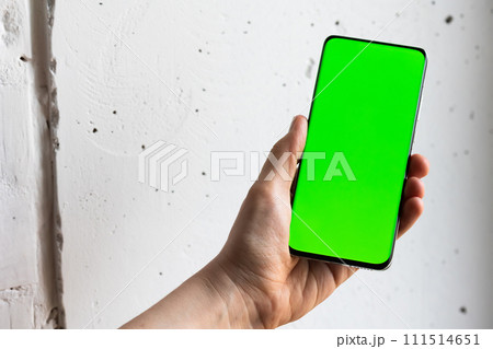 Mockup image of a person holding smart mobile phone with blank green screen. 111514651