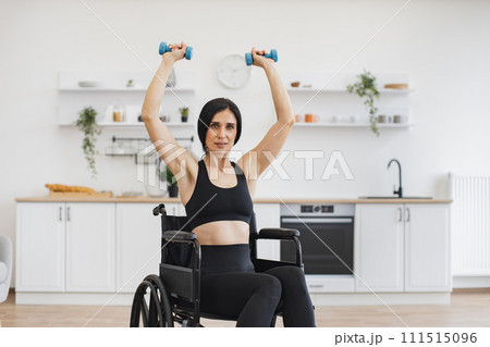 Caucasian person with disability holding dumbbells in raised arms. 111515096