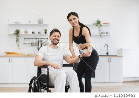 Handicapped mature man training with his wife or female trainer using dumbbells. Handicapped mature man training with his wife or female trainer using dumbbells. 111515463