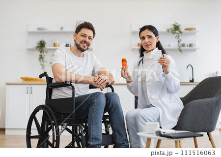 Female therapist with pills on hands consulting mature patient with disability Female therapist with pills on hands consulting mature patient with disability 111516063