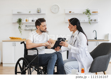 Caucasian female doctor checking up condition of bearded male patient at home. 111516107