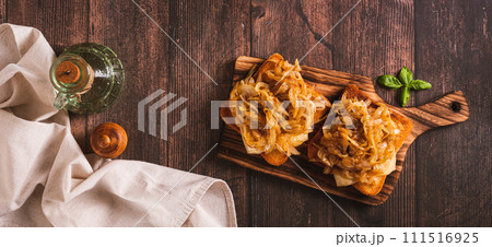 Homemade bruschetta with cheese and fried onions on a wooden board top view web banner 111516925