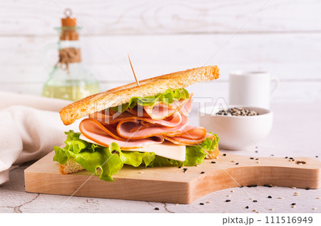 Sandwich with ham, cheese and onion on a wooden board on the table 111516949