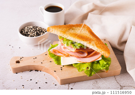 Toast sandwich with ham, cheese and herbs on a wooden board on the table Toast sandwich with ham, cheese and herbs on a wooden board on the table 111516950