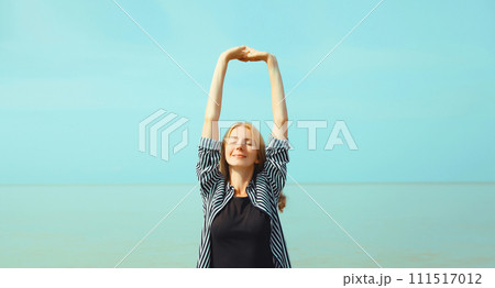Summer vacation, happy relaxing woman meditates on the beach on sea Summer vacation, happy relaxing woman meditates on the beach on sea 111517012