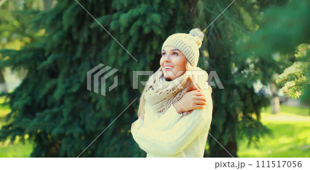 Winter portrait of happy smiling young woman in hat, scarf in forest on christmas tree background Winter portrait of happy smiling young woman in hat, scarf in forest on christmas tree background 111517056