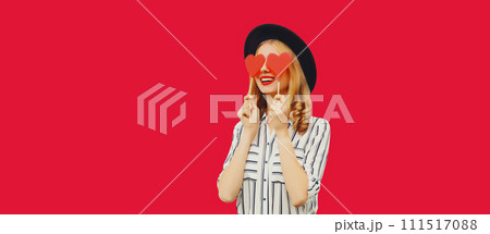 Portrait of happy cheerful young woman with sweet red heart shaped lollipop on stick on pink 111517088