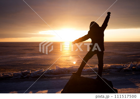 Man on rock on the sea in the ice - silhouette 111517500